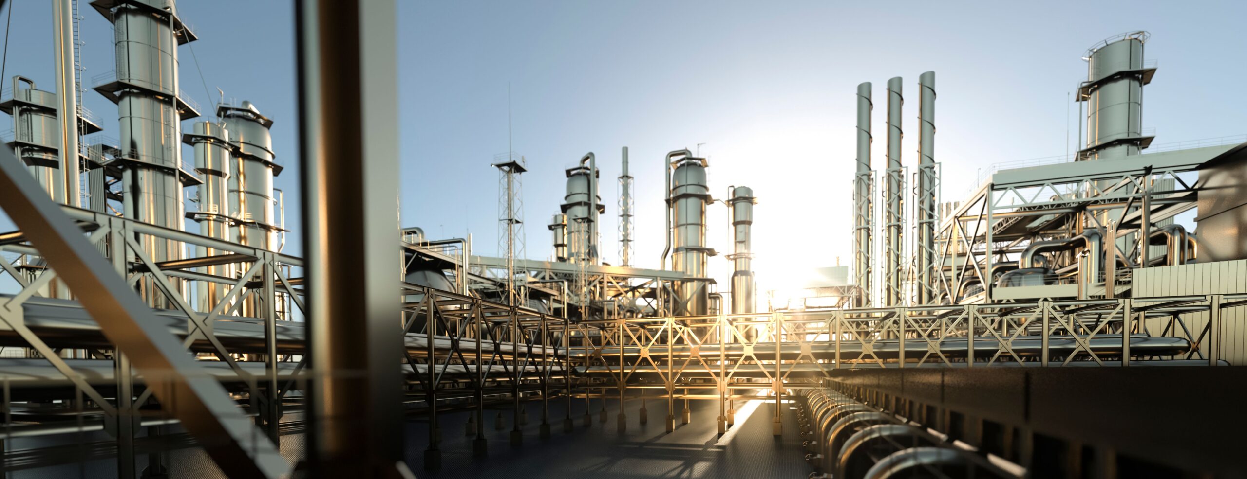 Industrial facility with tall metallic structures and piping, bathed in sunset light, illustrating energy production infrastructure.
